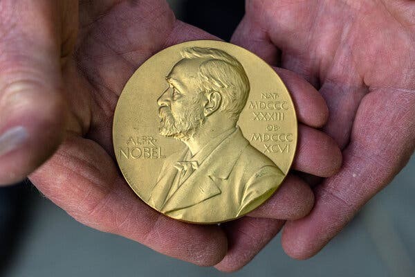 Hands hold out the coveted Nobel Prize.